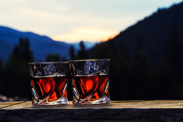 shot of whiskey at sunset dramatic sky on mountain landscape background