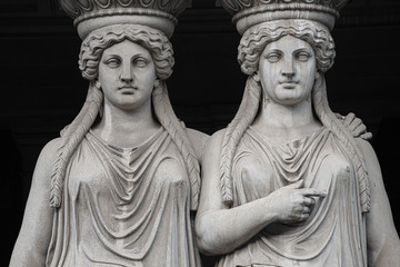 Statue of two sensual Roman renaissance era women at Parliament building in Vienna, Austria, isolated at black background