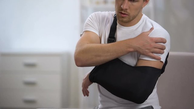 Man wearing arm sling feeling pain in shoulder, result of trauma, orthopedics