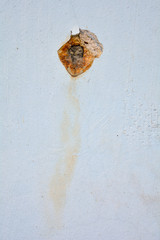 White concrete wall with rusted hole