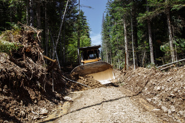 Construction of a road. Bulldozer at work. Destruction a forest. Broken and fallen trees. with a...