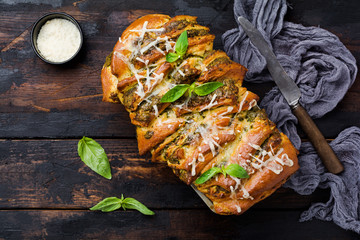 Pull-apart bread with Italian pasta pesto, basil and parmesan cheese in baking form over old wooden...
