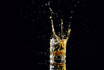 Isolated shot of whiskey with splash on black background, brandy in a glass