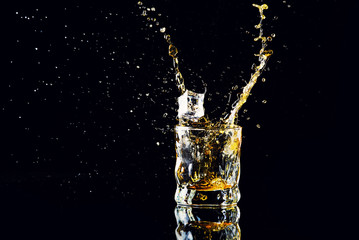 Isolated shot of whiskey with splash on black background, brandy in a glass