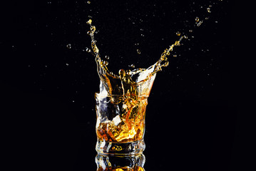 Isolated shot of whiskey with splash on black background, brandy in a glass
