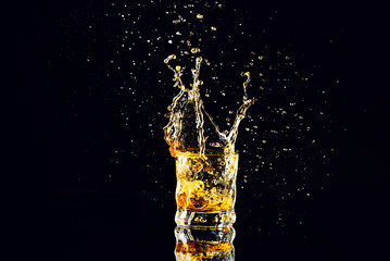 Isolated shot of whiskey with splash on black background, brandy in a glass