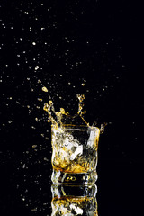 Isolated shot of whiskey with splash on black background, brandy in a glass