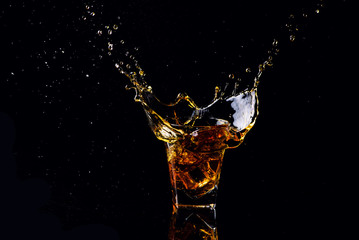 Isolated shot of whiskey with splash on black background, brandy in a glass