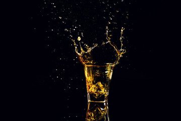 Isolated shot of whiskey with splash on black background, brandy in a glass