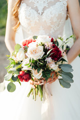 Beautiful bride is holding a wedding colorful bouquet.