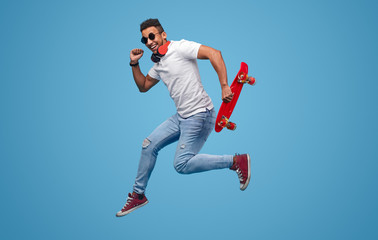 Black hipster with skateboard jumping and smiling