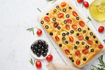 Fototapeta na wymiar Focaccia with tomatoes, olives and rosemary, copy space, top view. Whole Italian flat bread, bottle with oil