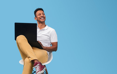 Cheerful black student with laptop looking away - obrazy, fototapety, plakaty