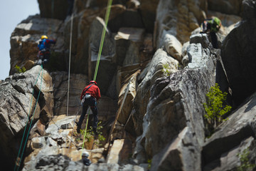 Group of climbers during the competition against the backdrop of a complex rocky terrain. Tilt-Shift effect.