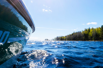 Side view Speeding fishing motor boat with drops of water. Blue ocean sea water wave reflections...