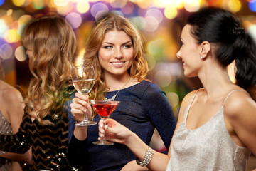 celebration, bachelorette party and holidays concept - happy women or female friends clinking glasses at night club
