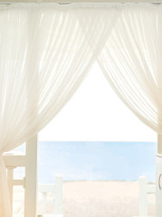 Beautiful beach and sea view behind white curtains
