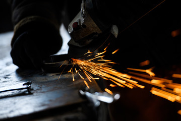 Metal grinding on steel pipe with flash of sparks close up