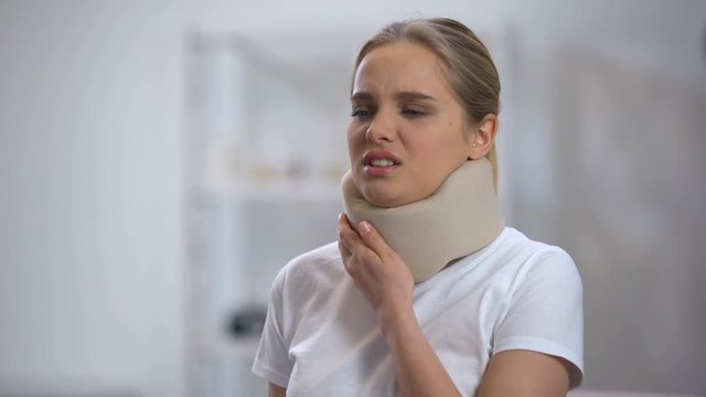 Young woman in foam cervical collar feeling sharp pain in neck, trauma result