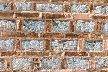 Beautiful old wall made of different bricks. Rough masonry with cement.