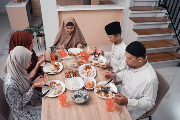 muslim family together pray before meals, a fast breaking meal served on a table