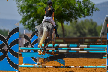 Young rider jumping over the obstacles during the horse jumping competition