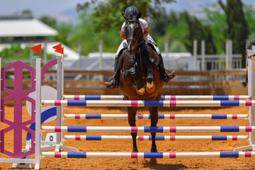 Young rider jumping over the obstacles during the horse jumping competition