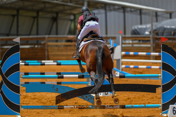 Young rider jumping over the obstacles during the horse jumping competition