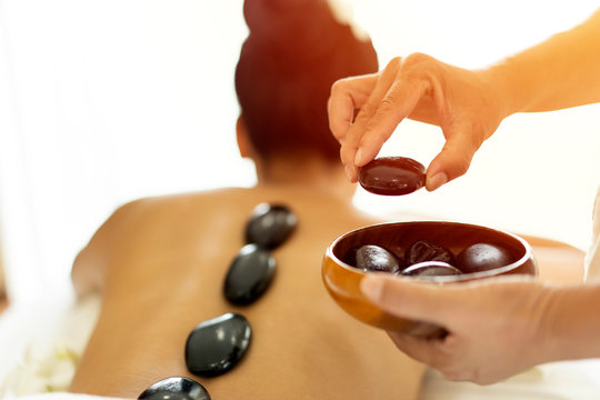 Asian woman getting hot stone massage while lying down on massage bed with traditional in spa salon and wellness center. Start up, Health Care ,Spa Beauty treatment, lifestyle modern woman concept