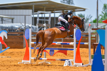 Young rider jumping over the obstacles during the horse jumping competition