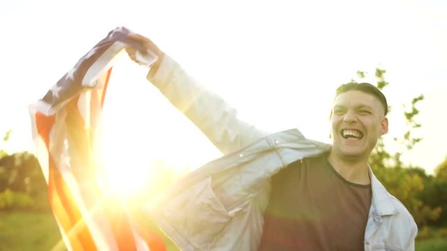 A young man in a denim jacket is waving a US flag and shouting. Sunset, Independence Day, July 4th