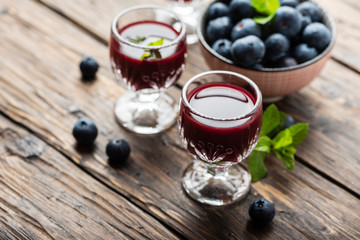 Sweet blueberry liqueur on the wooden table