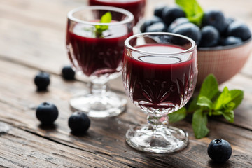 Sweet blueberry liqueur on the wooden table