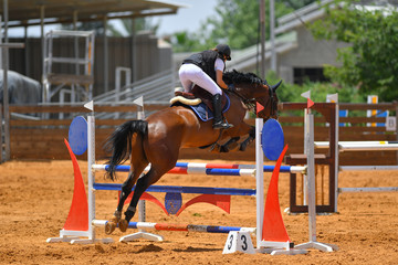 Young rider jumping over the obstacles during the horse jumping competition