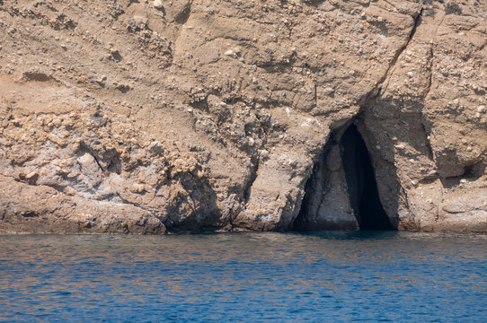 cave carved in the island's mountain seen from the boat