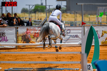 Young rider jumping over the obstacles during the horse jumping competition