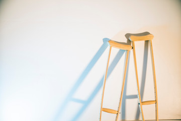 crutches stand at the light wall as a symbol of disability and injury