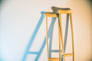 crutches stand at the light wall as a symbol of disability and injury