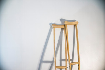 crutches stand at the light wall as a symbol of disability and injury