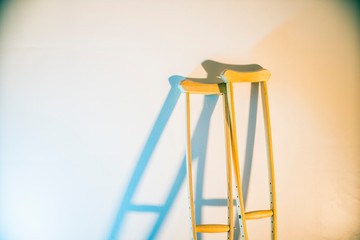 crutches stand at the light wall as a symbol of disability and injury