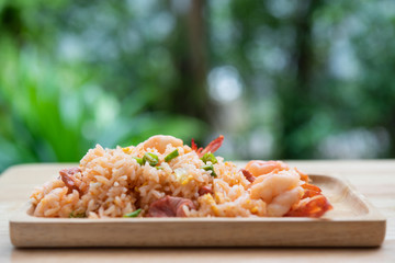 Delicious Thai fried rice with shrimp on wooden table with beauitful vase ,green blurred background