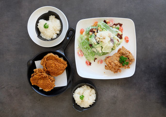 Caesar Salad serving with crispy fried chicken on dark surface table