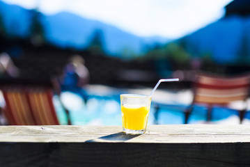 Fresh orange juice in glass on mountain landscape background