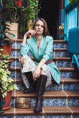 Young beautiful model with blond hair sitting on the stairs. Skin retouching.