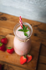 Close-up of strawberry smoothie with fresh mint in a jar on wooden background