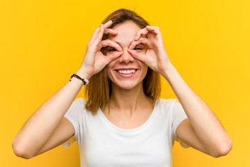 Young natural caucasian woman showing okay sign over her eyes