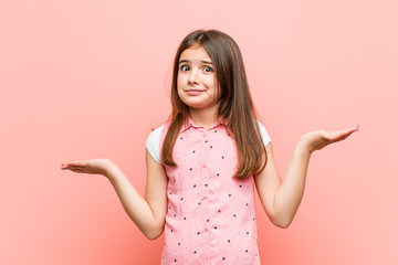 Cute little girl doubting and shrugging him shoulders in questioning gesture.