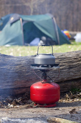 Tourist equipment for cooking tea and coffee on gas while traveling, amid smoke from the fire....
