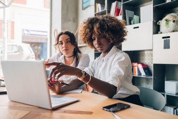 two multiracial young women working together in a co working office