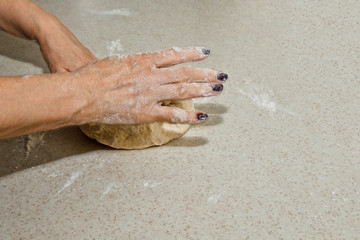 Female hands knead the dough with flour on a white kitchen table. Top view. baking preparation stage, cooking